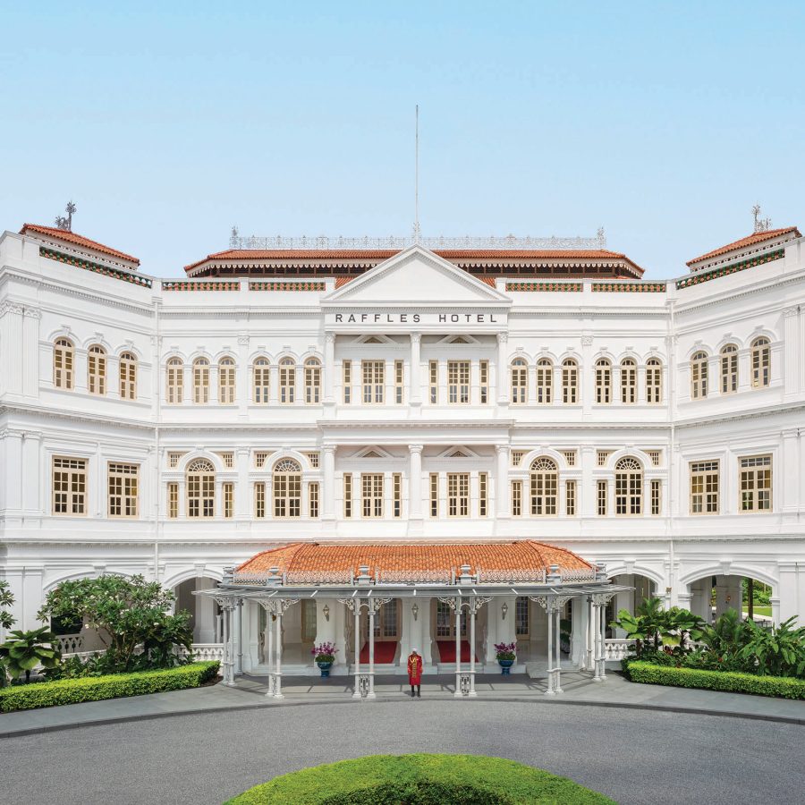 The exterior of Raffles Hotel Singapore is white with classical architectural elements like arched windows and moderate embellishments.